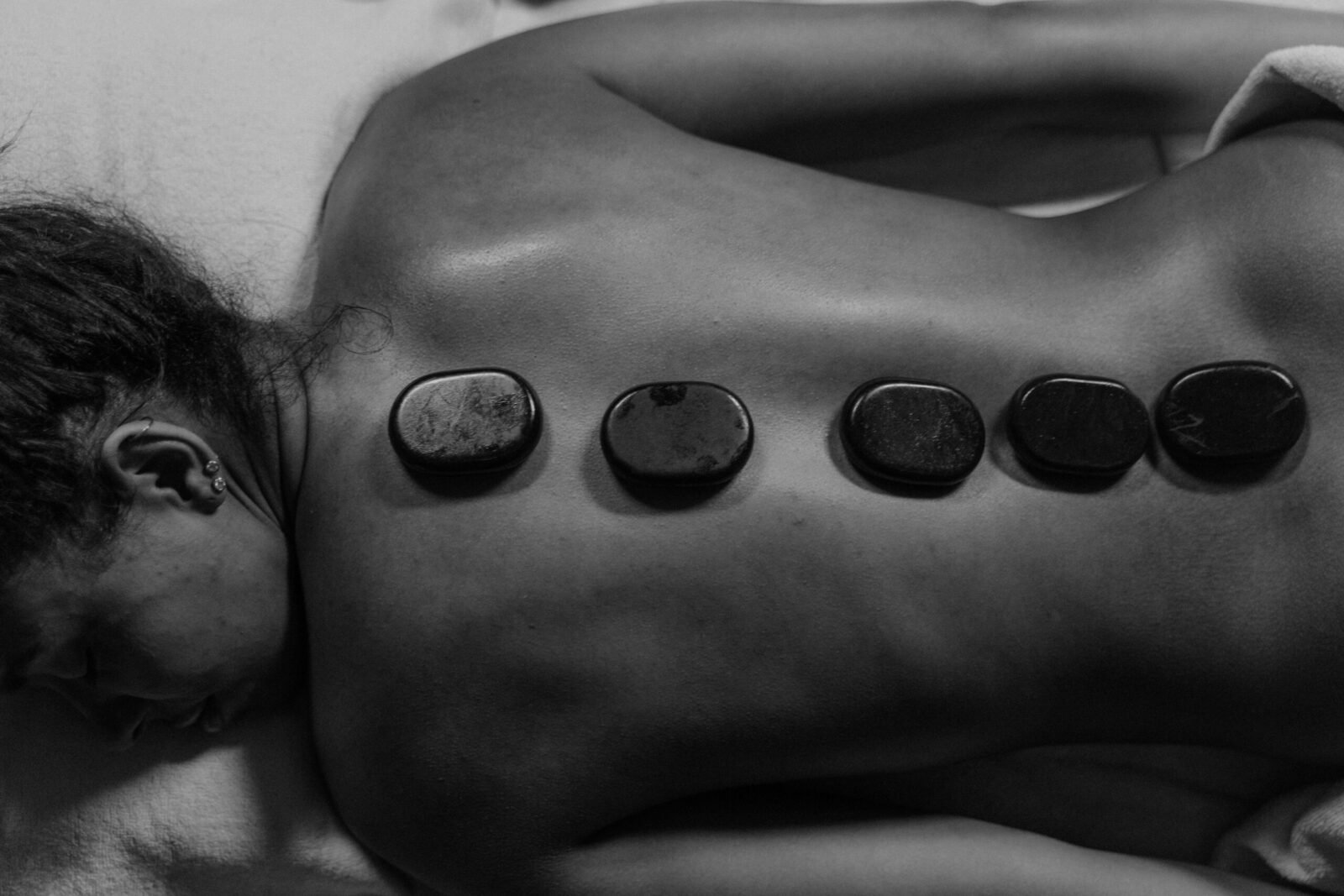 A calming black and white image of hot stone therapy on a woman's back, promoting wellness.